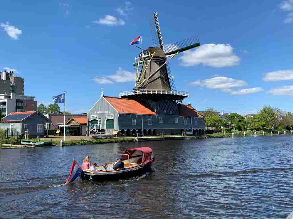 a boat on the Vliet with a Dutch windmill in the background on a sunny summer day.