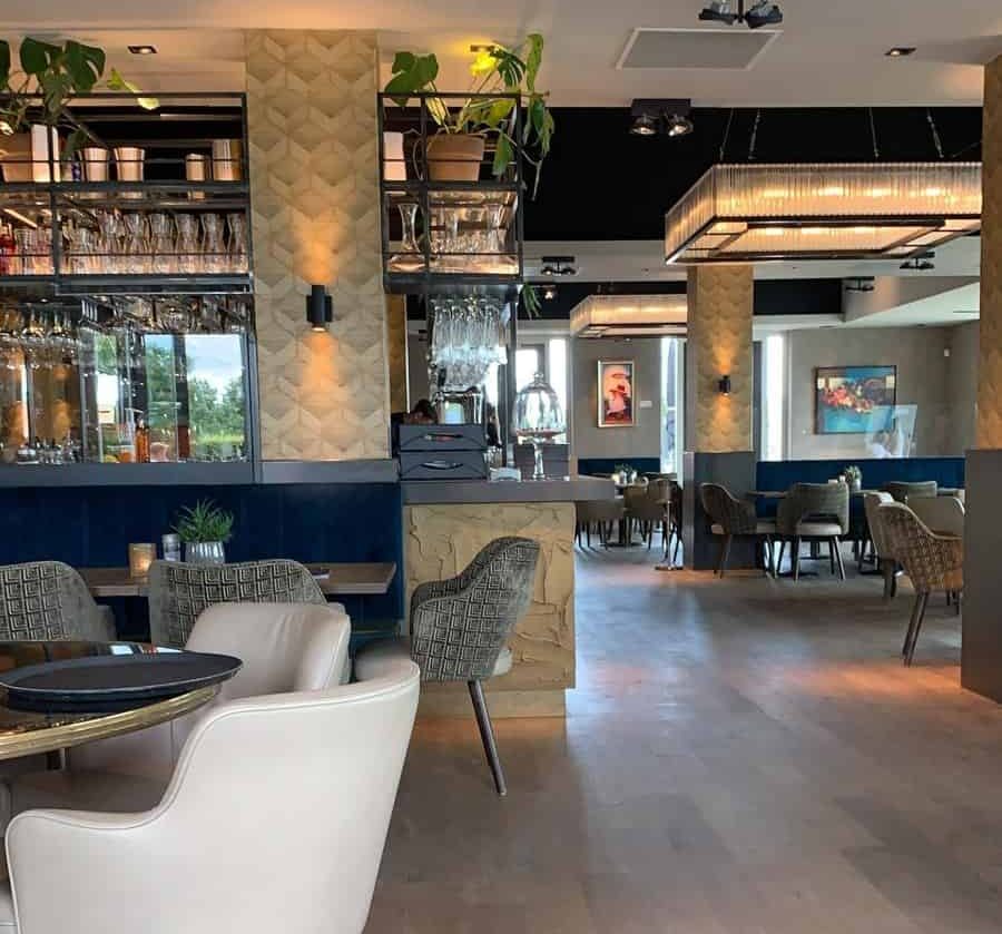 Interior of the Hof van Saksen Grand Café, showcasing a stylish restaurant space with contemporary decor, comfortable seating arrangements, hanging green plants, and elegant lighting, inviting guests to dine in a modern and welcoming atmosphere
