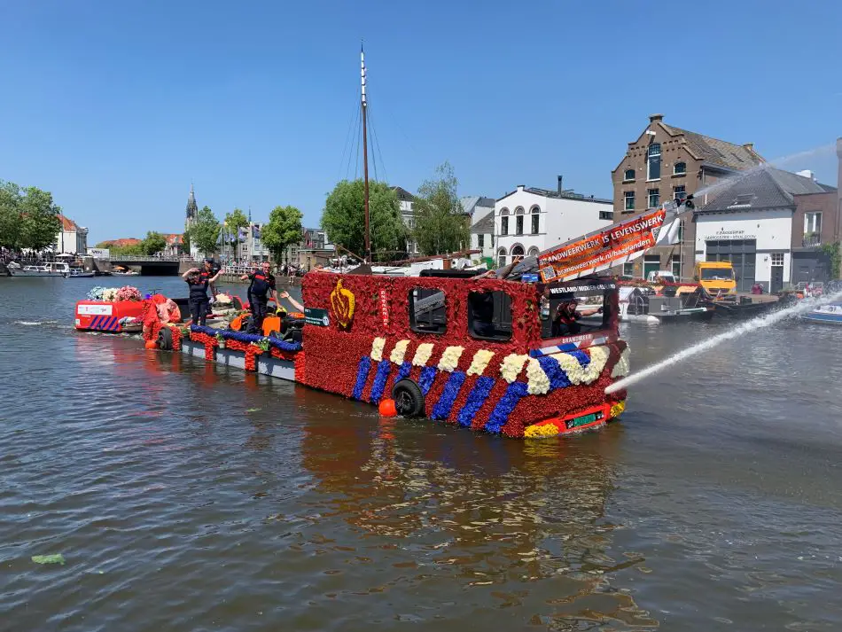 Boat decorated as firefighter truck with flowers in floating flower parade in 2023